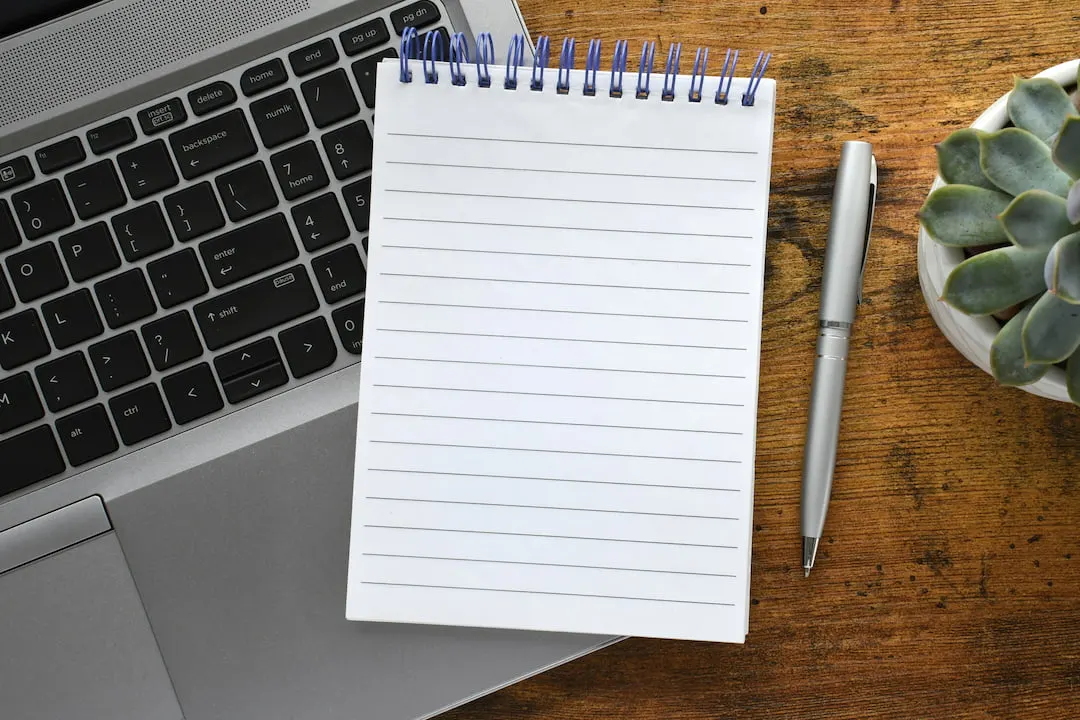 Blank notepad and pen resting on a laptop keyboard