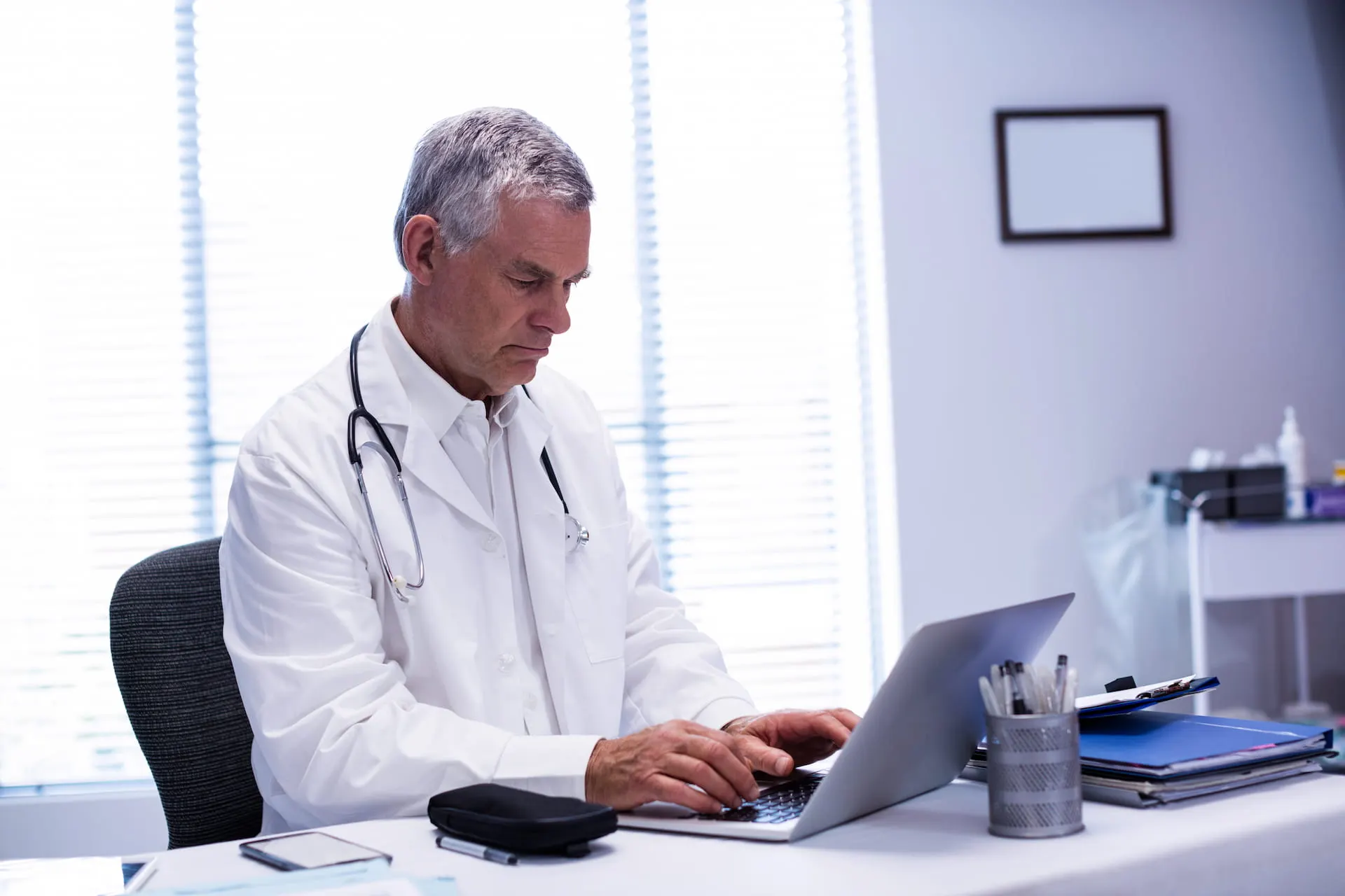 Doctor writing an email at a laptop in his office