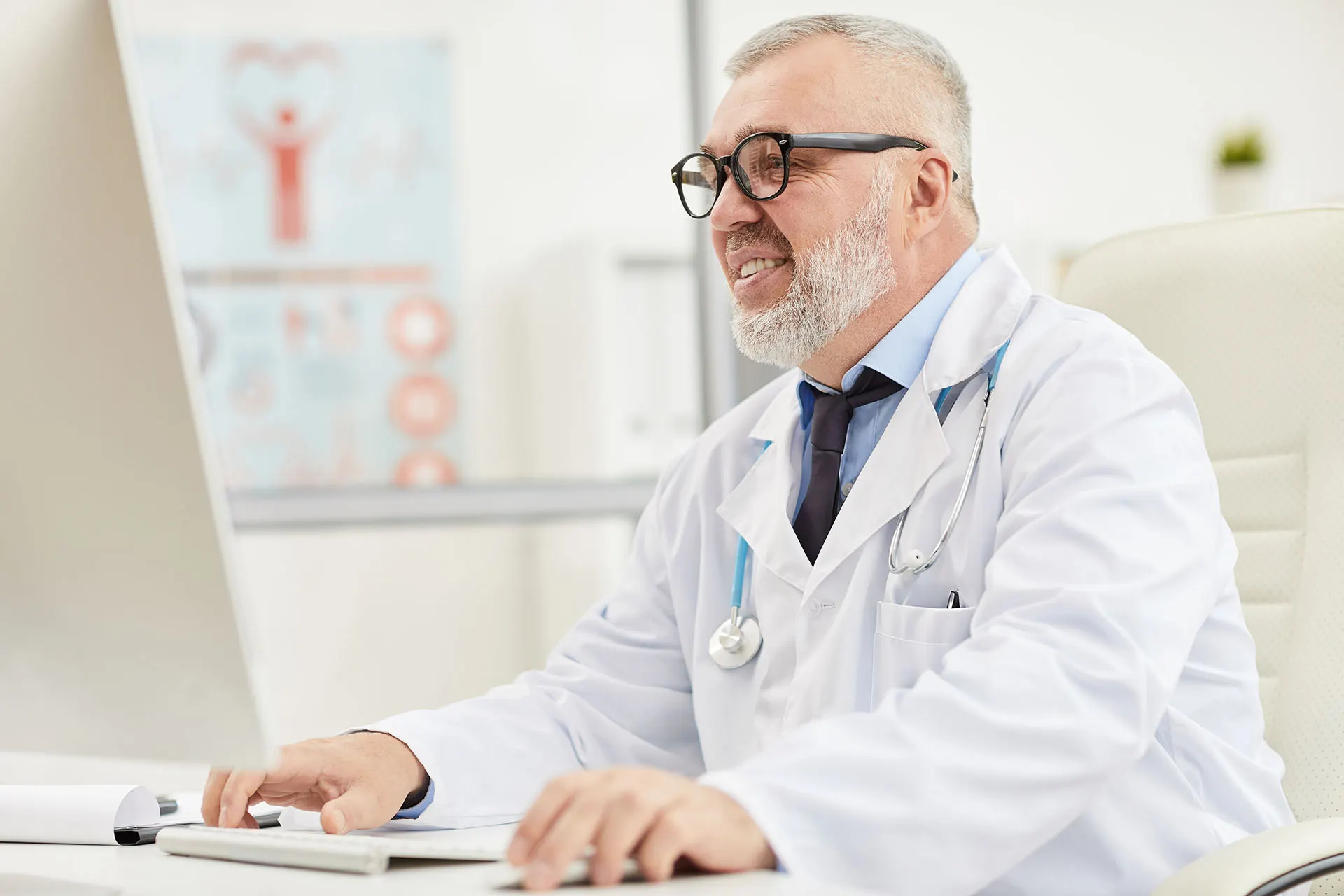 Doctor smiling while working at a desktop computer